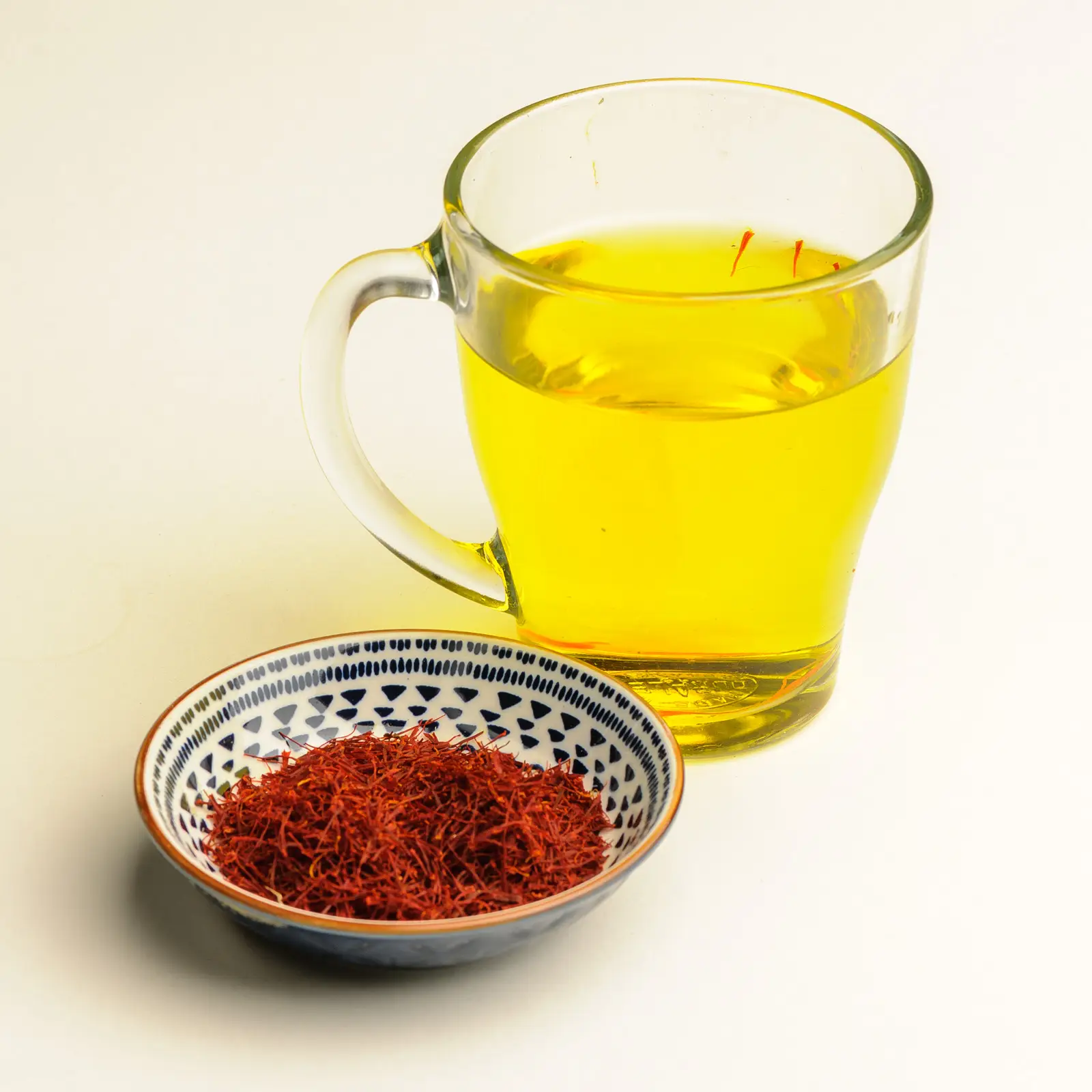 Schaaltje superieure Iraanse saffraan en een theeglas met prachtige lichtgele thee.